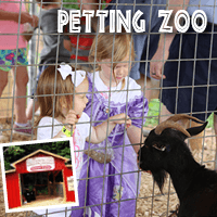 Two little girls petting a black goat at the Jaemor Farms petting zoo