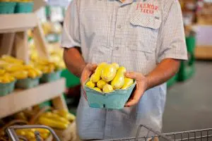 Man holding a small basket of yellow squash