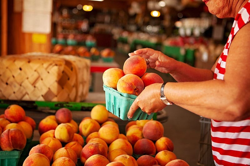 Woman holding small basket of peaches